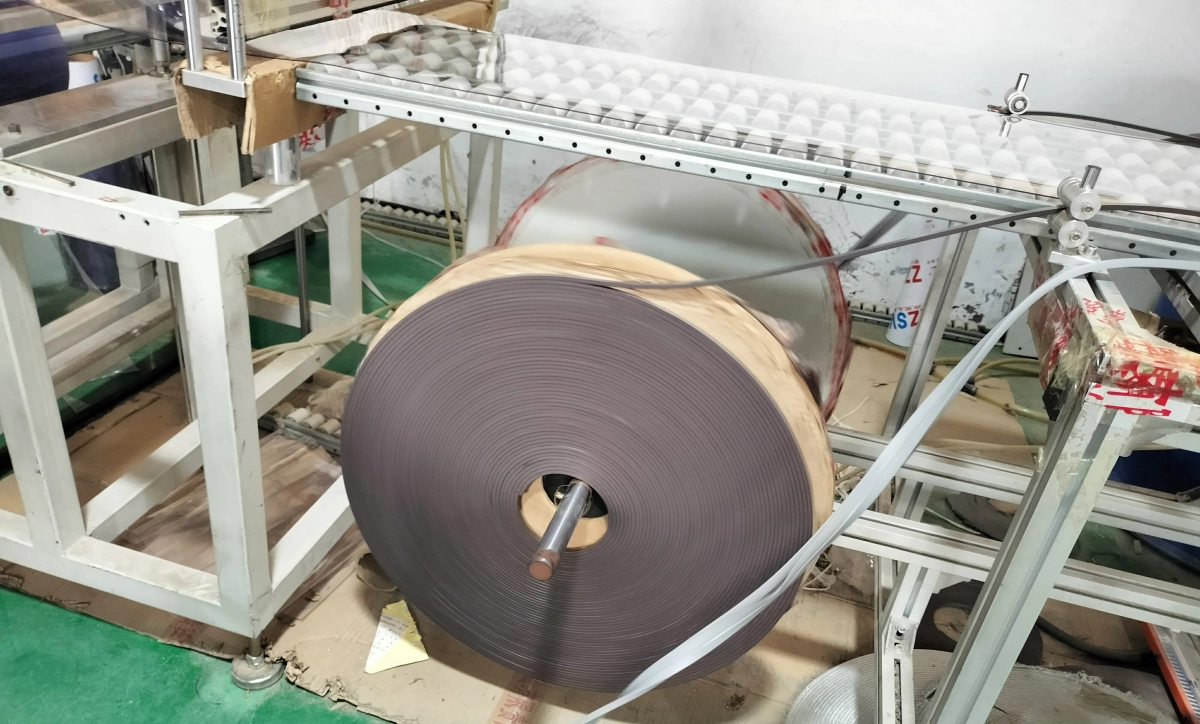 A factory worker inspecting rolls of high-quality PVC material ready for magnetic curtain production.